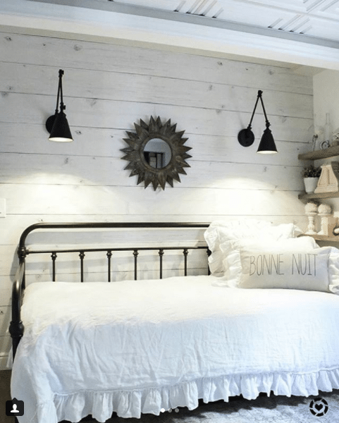 guest room with Whitewashed Timber wallpaper on the wall with a white daybed and black railing. Two black sconces hang above the bed. A pillow says "bonne nuit"