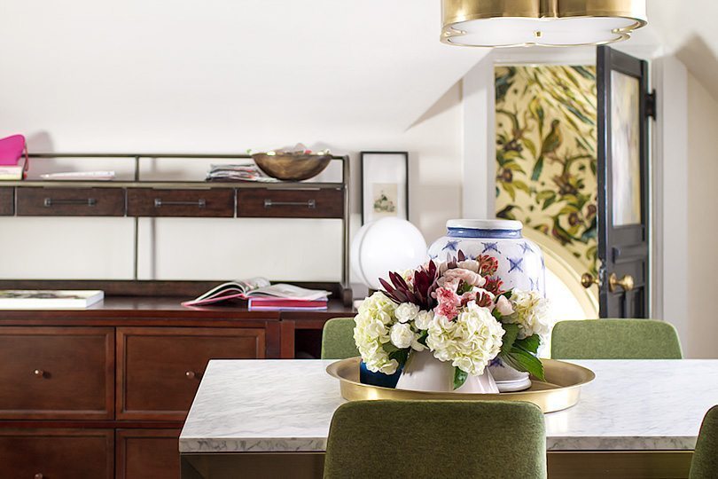 Table with floral arrangement in the center. In the background you can see the open door to the closet where the wallpaper of Orinthology by Milton & King can be seen peeking through.