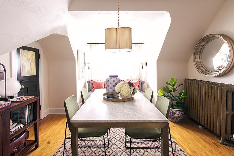 a wide shot of Nicole Balch's office space. You can see a table in the middle with four olive green chairs on top of the rug she brought back from Morocco. 