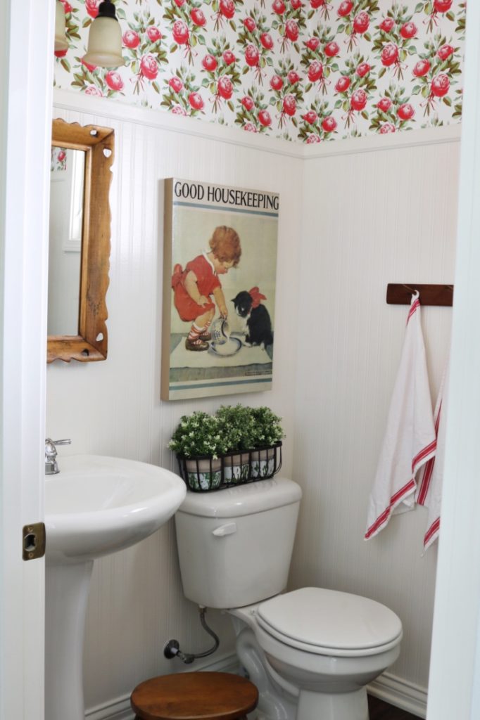 vintage bathroom with floral wallpaper around the top of the room. 