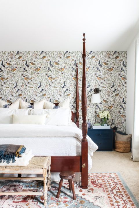 Woodland Birds wallpaper in a bedroom behind a bed with white linens. Very tall wooden bed posts at each corner of the bed.