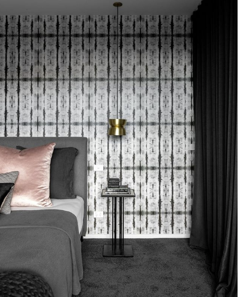 Stalactite Wallpaper behind a grey bed with a small pendant lamp hanging on the right side of the bed