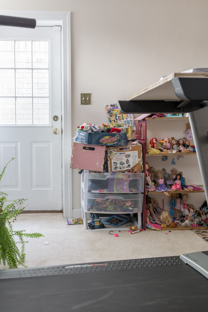 Jewel Marlowe Basement Makeover • Before the makeover with plain white walls and various toys stacked against the wall