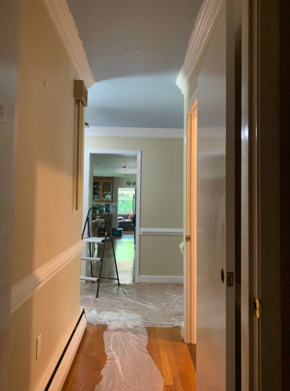 This picture is of a narrow hallway with the walls painted beige and the chair rail painted white