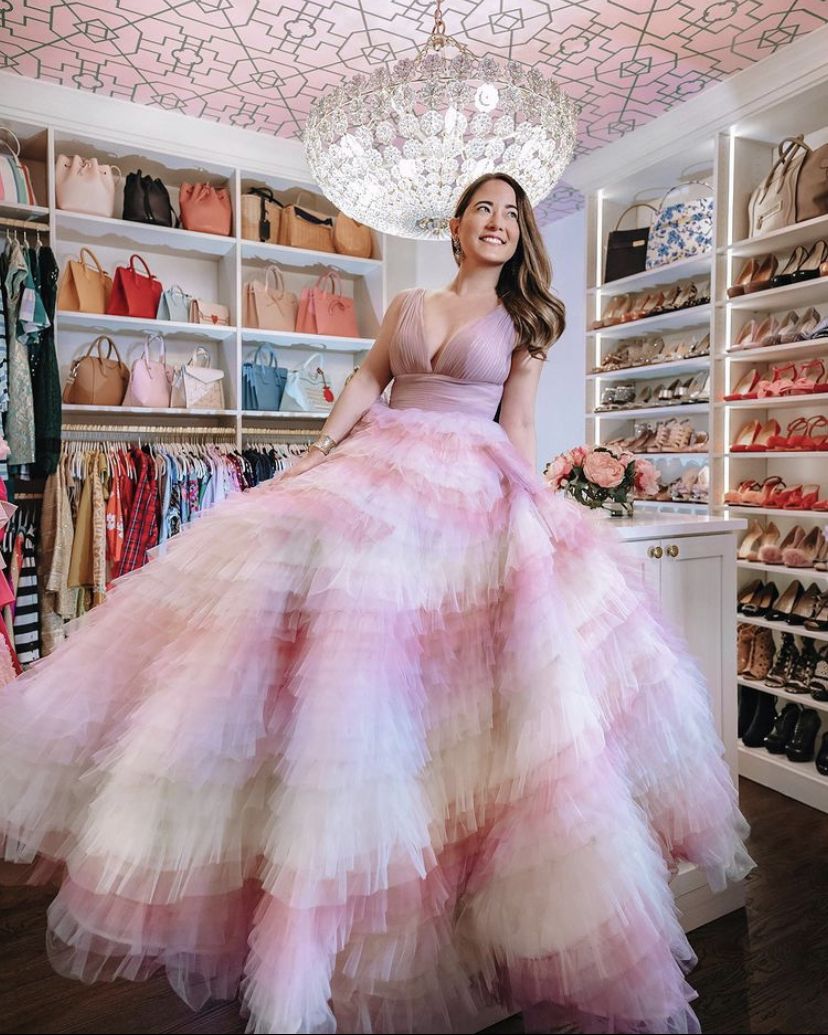 Jennifer Lake from Style Charade posing in a pink dress with a fluffy fair skirt and camisole in her wardrobe closet with a crystal chandelier and pink Trellis Wallpaper by Bethany Linz on the ceiling